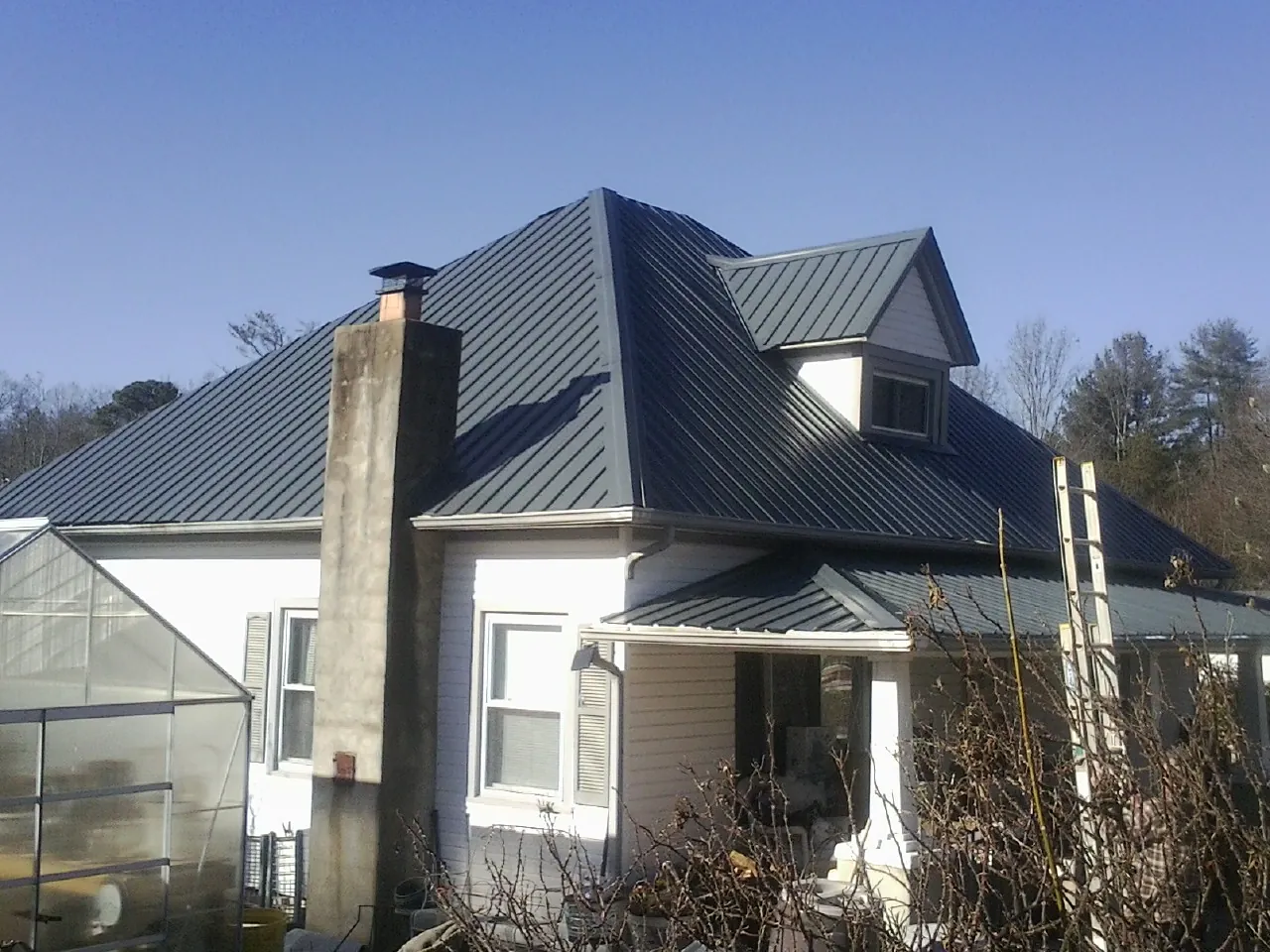Dark blue standing seam metal roof on a white farmhouse with dormer — Slate & Tile Roof Repair by Roofing Brothers in Bird Island