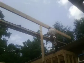 Carpenter setting a ridge beam over a new addition frame — Ice Dam Removal by Roofing Brothers in Bird Island