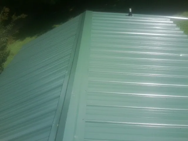 New green metal panels meeting at the ridge of a roof — Flat Roof Repair work by our crew in Bird Island