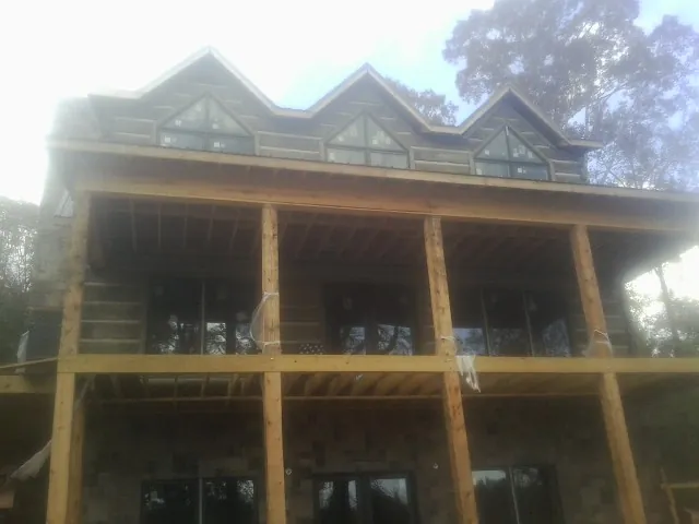 Dormers and porch framing on a large log home under construction — Roof Coating work by our crew in Bird Island