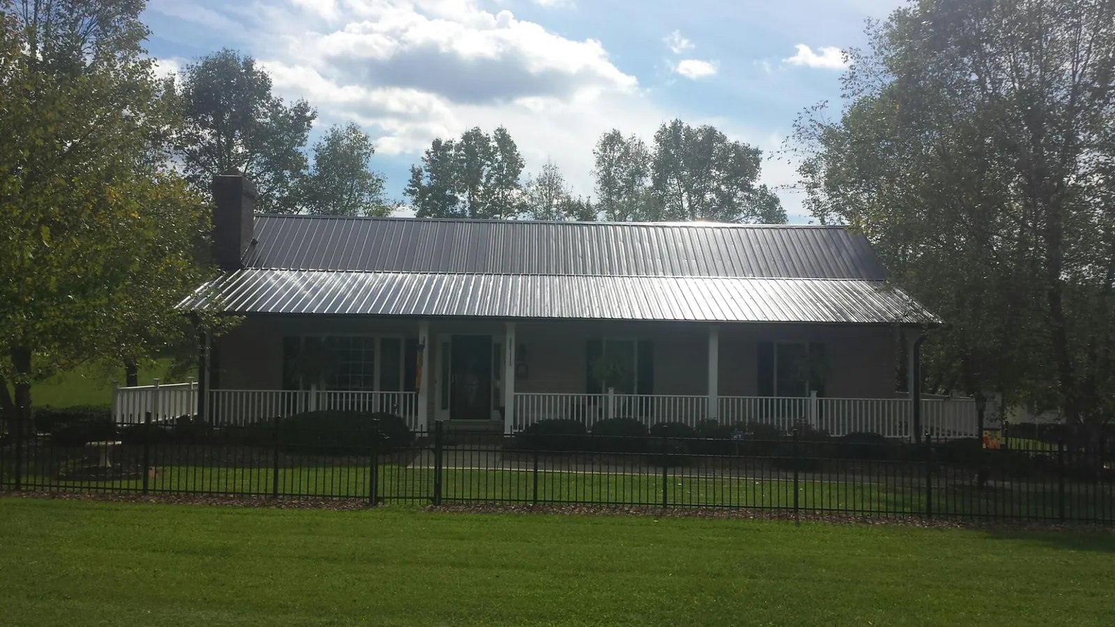 Gray metal roof on a brick ranch with a full width front porch — Gutter Guard Installation work by our crew in Bird Island