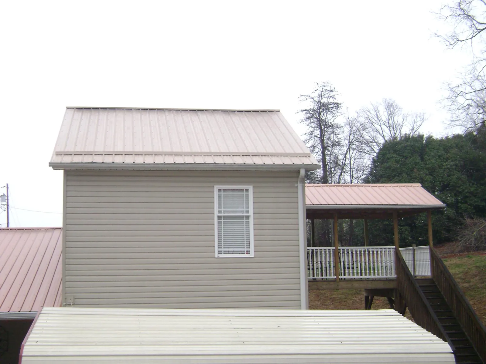 Tan metal roofs on a two story addition and attached porch, from a Roof Replacement job in Bird Island