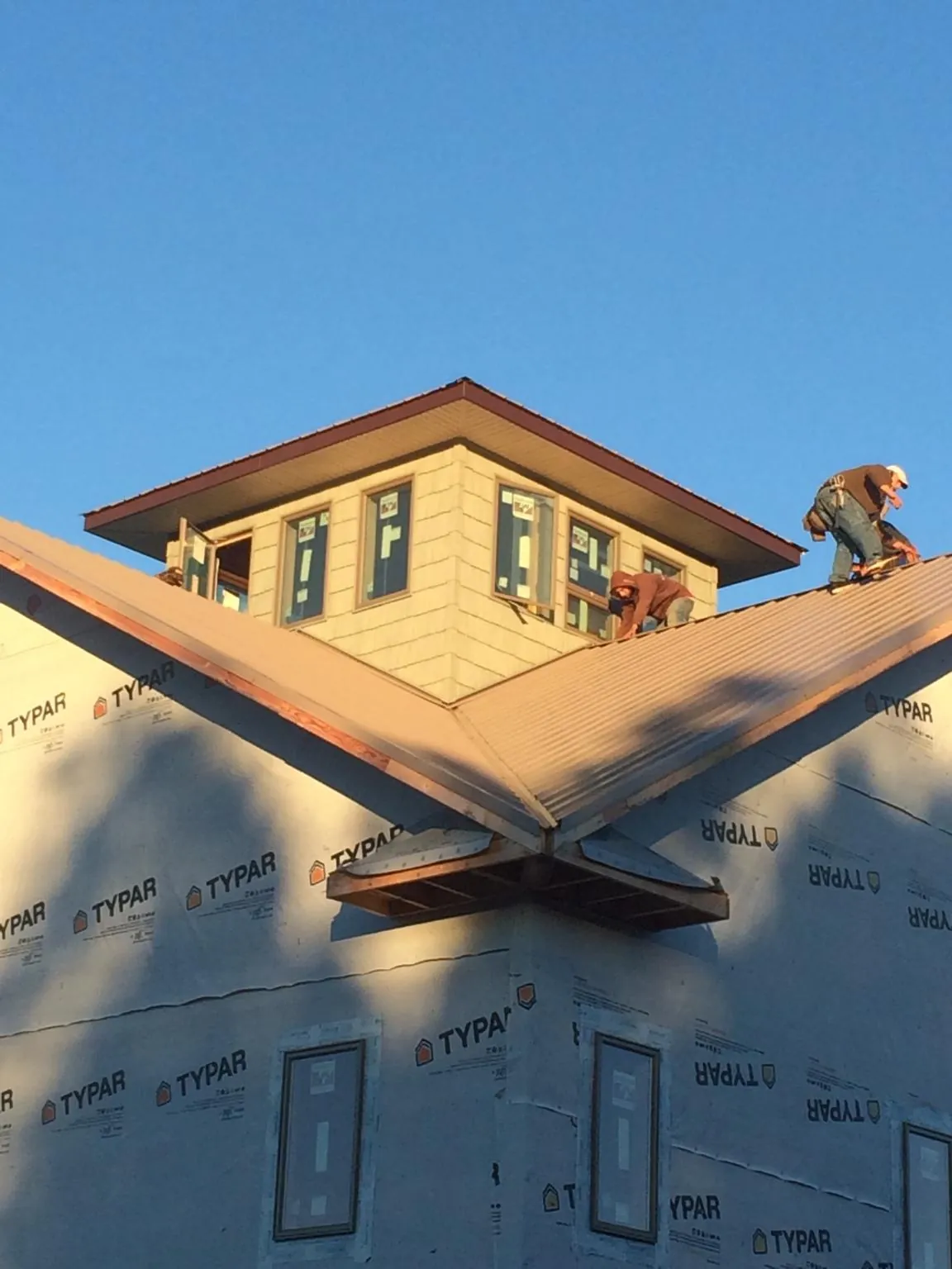 Roofers working around a rooftop cupola on a new metal roof at sunset — Roof Waterproofing in Bird Island by Roofing Brothers